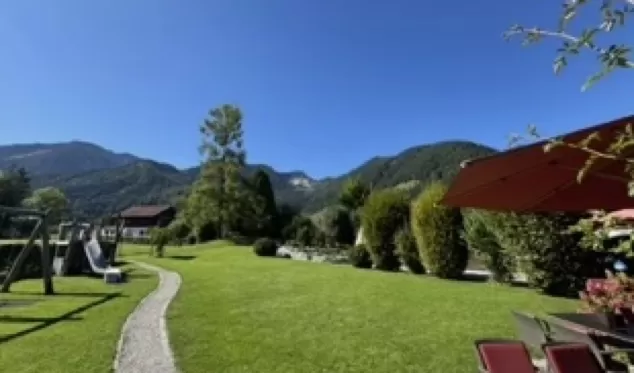 Terrassenausblick über grünen Rasen auf Berge unter blauem Himmel