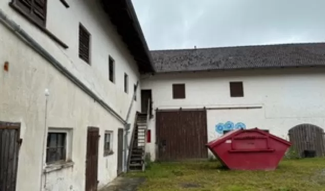 Aussenansicht des Hofs mit Holztor als Zugang zum Scheunentrakt