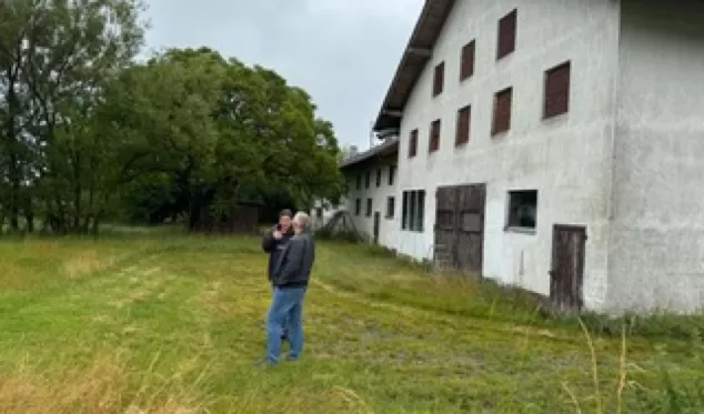 zwei Personen unterhalten sich vor dem Vierseithof